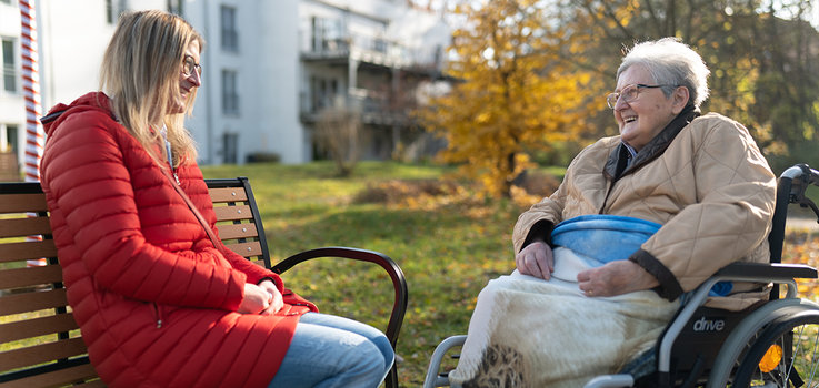 Bild | Fröhliche Pflegerin und Seniorin im Park